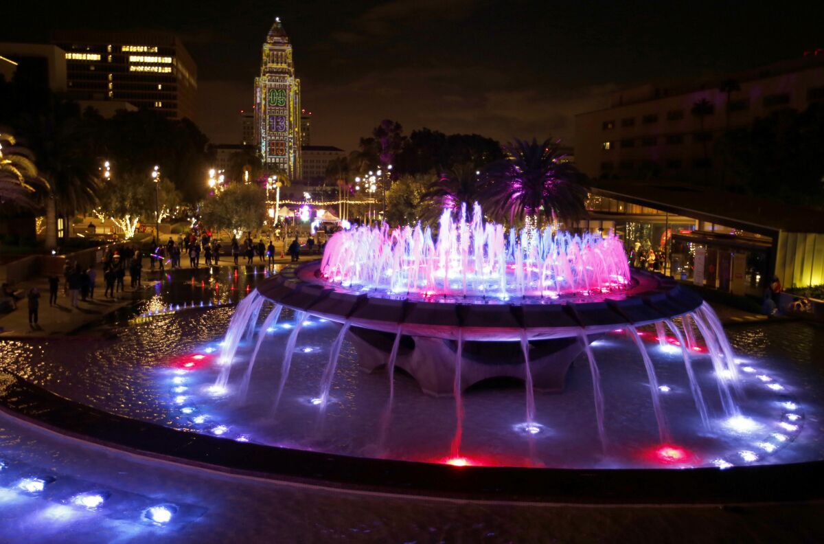Grand Park's fountain glows with a gleaming City Hall in the background.