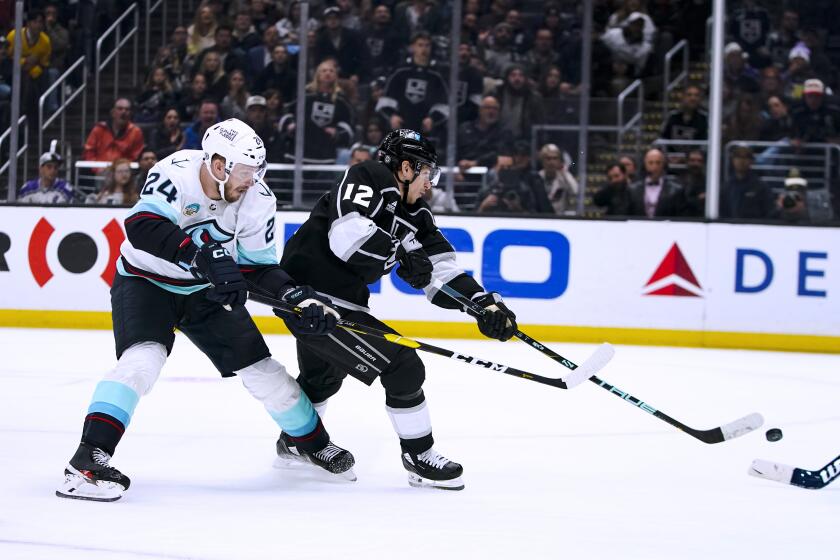 Los Angeles Kings left wing Trevor Moore (12) shoots as Seattle Kraken defenseman Jamie Oleksiak (24) chases during the second period of an NHL hockey game Wednesday, Dec. 20, 2023, in Los Angeles. (AP Photo/Ryan Sun)