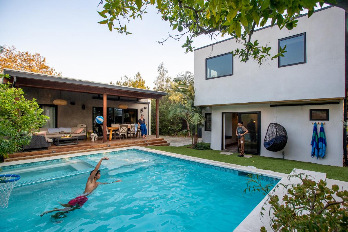 Two boys play in a pool in a backyard