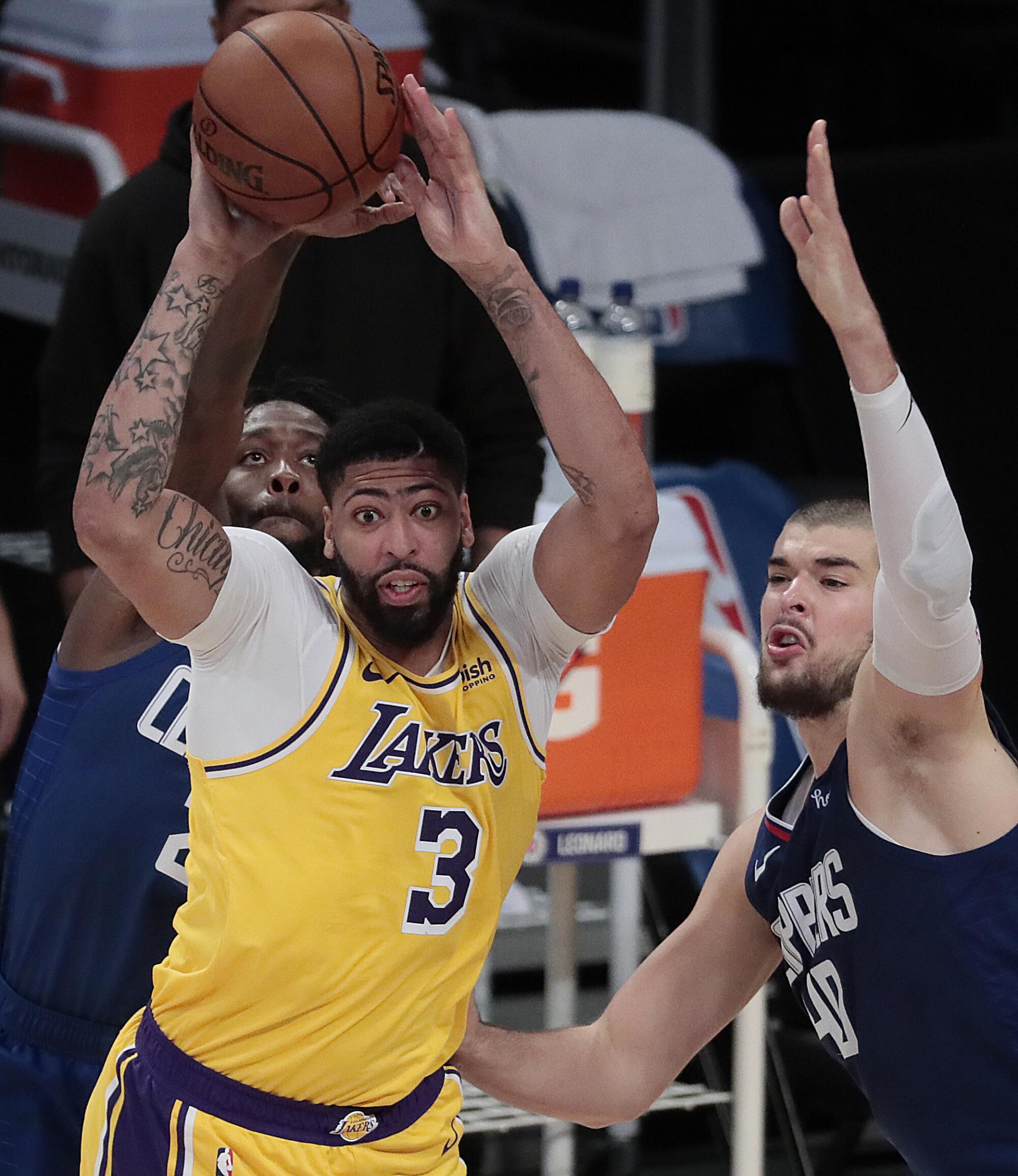Lakers forward Anthony Davis is defended by Clippers guard Patrick Beverley and center Ivica Zubac.