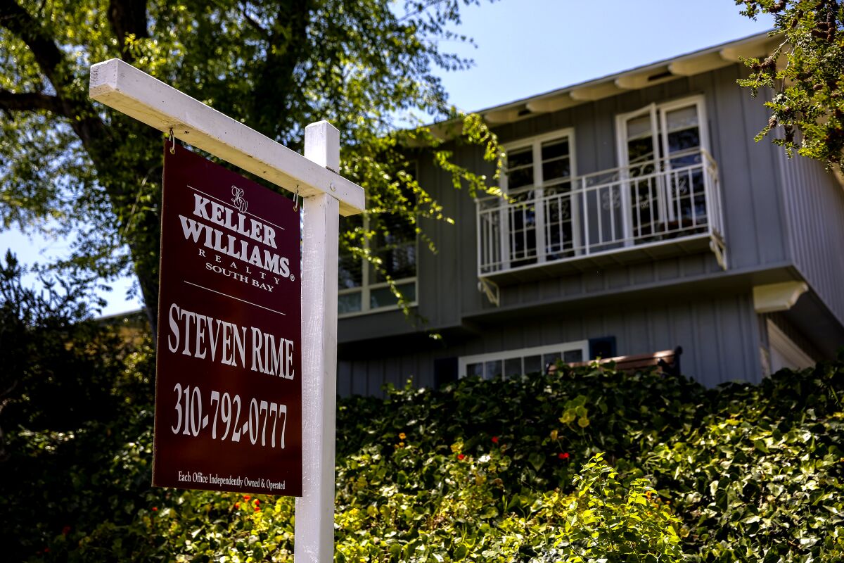 A realtor's advertising sign hangs outside a home.