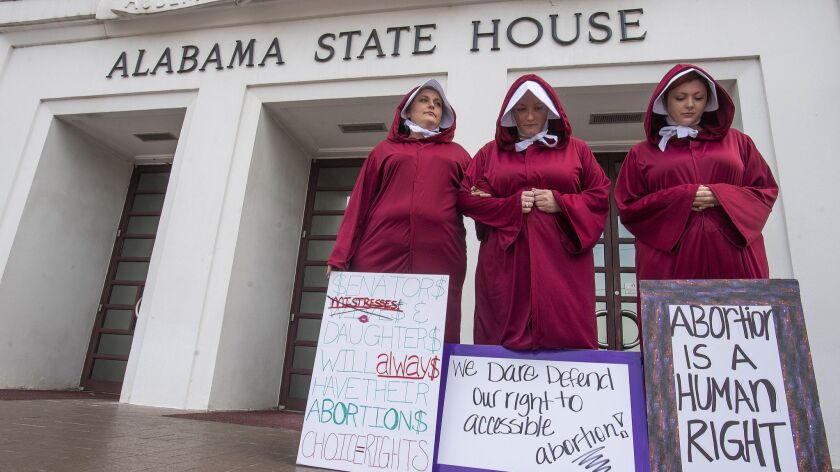 Abortion rights activists dressed as handmaids, or reproductive surrogates, from the book and TV series “The Handmaid’s Tale” demonstrate outside the Alabama State House in Montgomery against a bill to ban abortion.