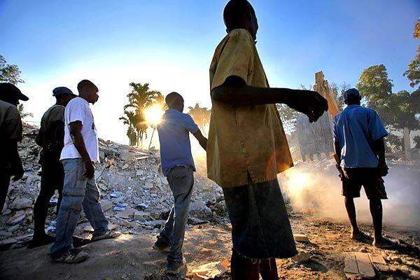 Scrap metal collectors wait for a backhoe to finish moving chunks of a fallen building before scrambling to salvage steel rebar in Port-au-Prince, the Haitian capital. Since the earthquake, salvage activity has exploded into all areas of the city instead of only the dump.