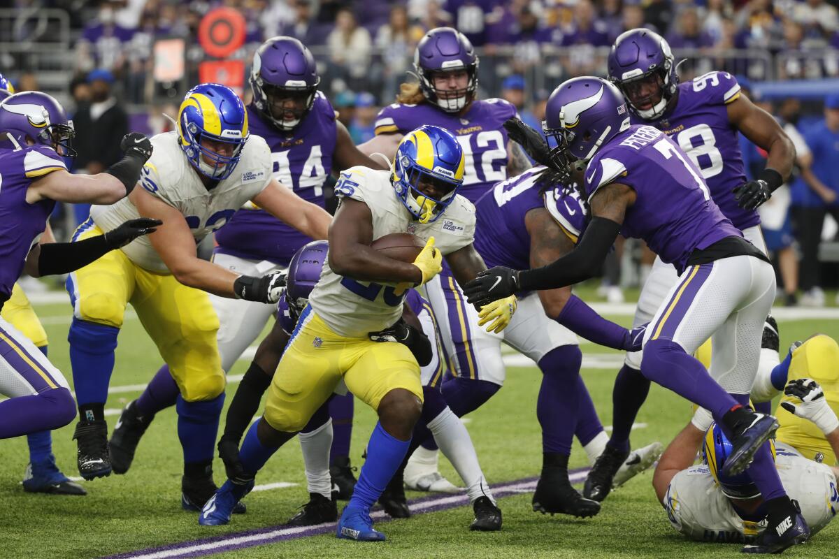 Rams running back Sony Michel (25) runs from Minnesota Vikings defenders in the first half.