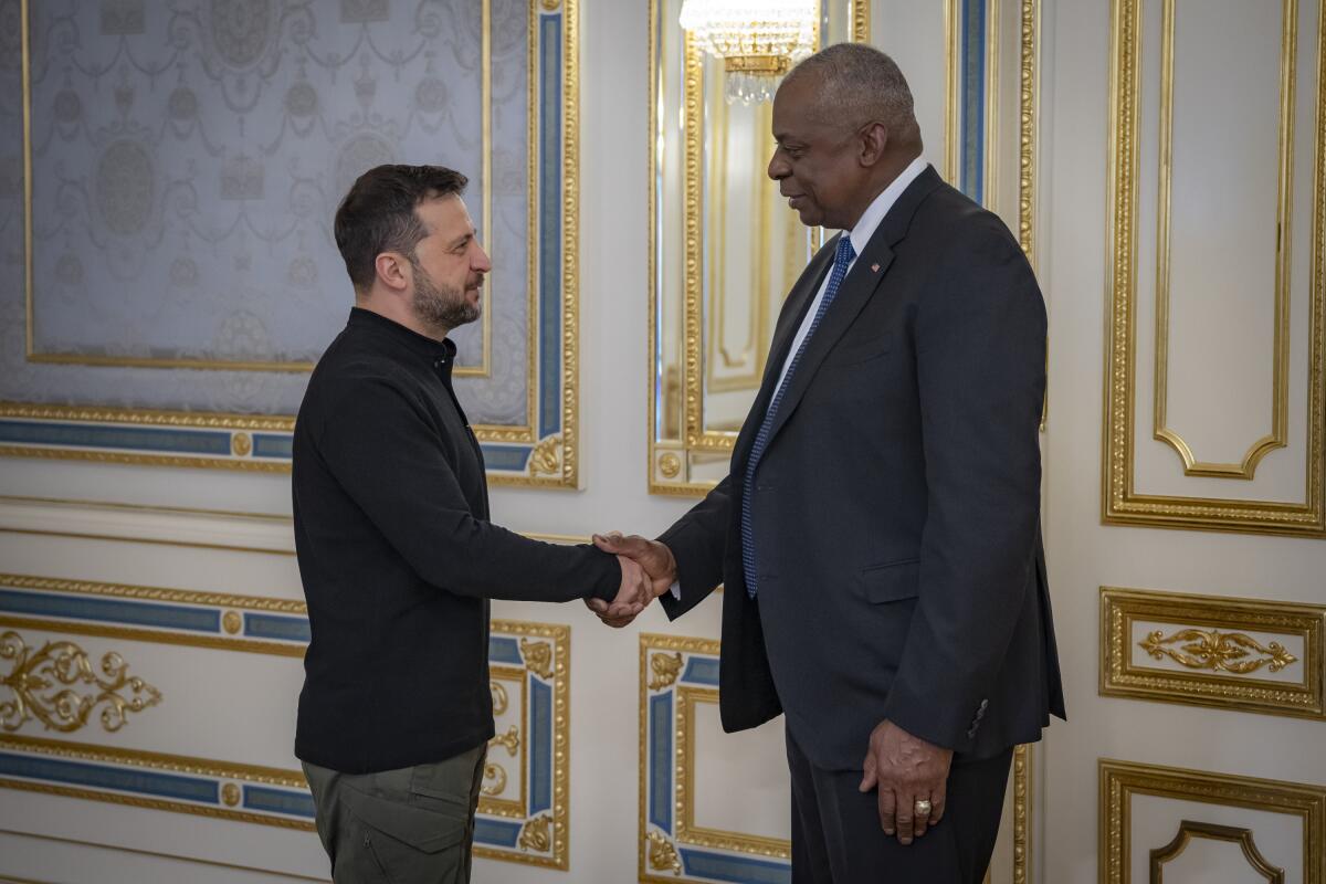 Volodymyr Zelensky shakes hands with Lloyd J. Austin III.