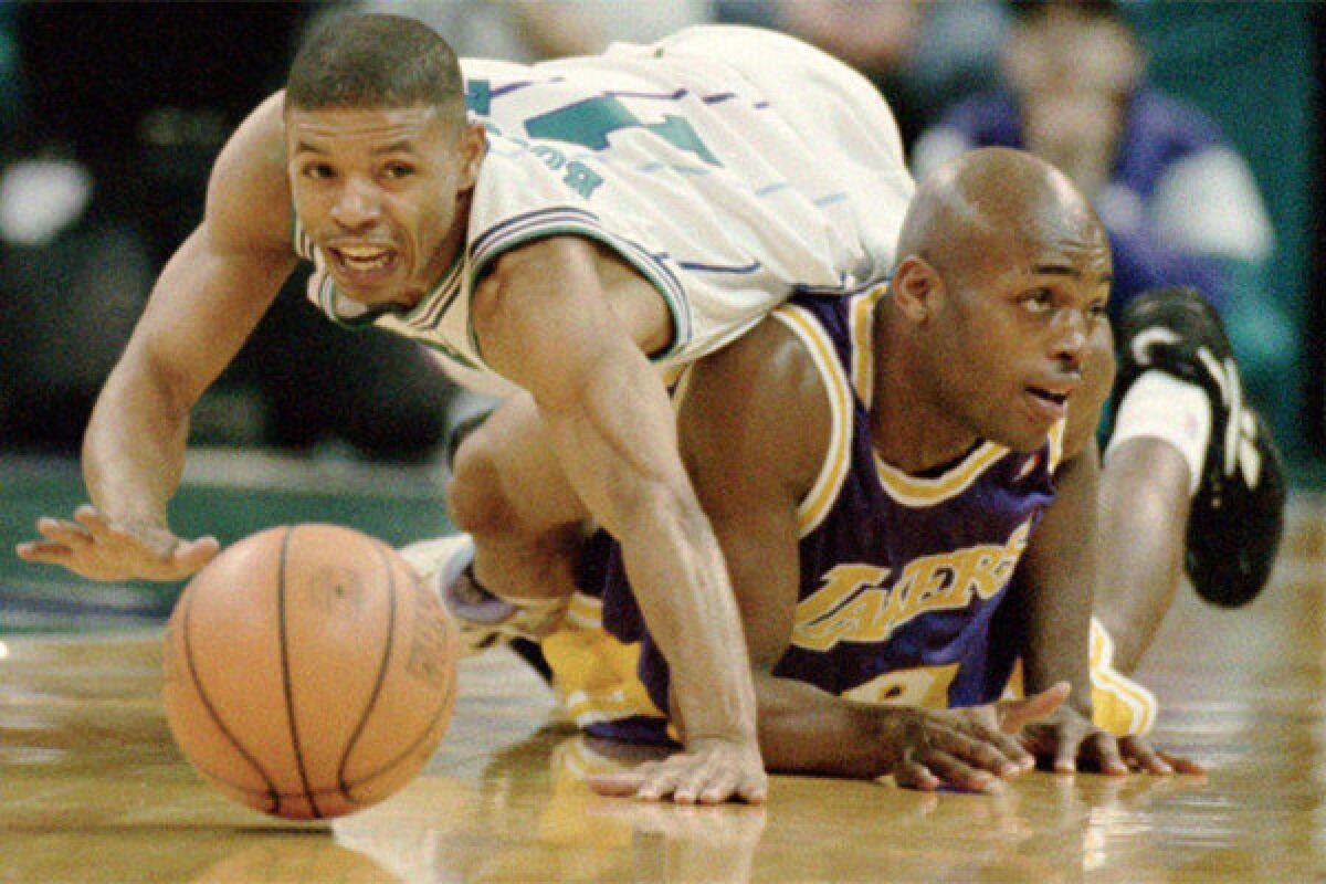 Charlotte Hornets guard Muggsy Bogues climbs over Lakers guard Nick Van Exel during a 1995 game at the Charlotte Coliseum.