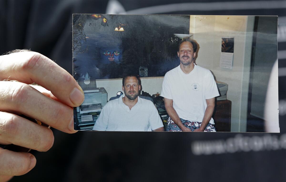 A man's hand holds a photograph showing two men