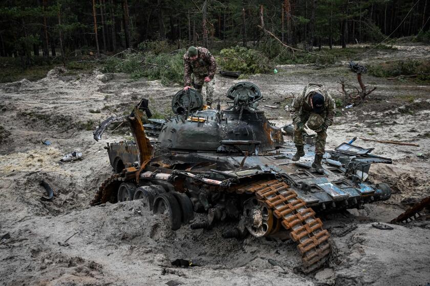 TOPSHOT - Ukrainian servicemen inspect a destroyed Russian tank near Kivsharivka village in a suburb of Kupiansk, Kharkiv region on December 15, 2022, amid the Russian invasion of Ukraine. (Photo by SERGEY BOBOK / AFP) (Photo by SERGEY BOBOK/AFP via Getty Images)