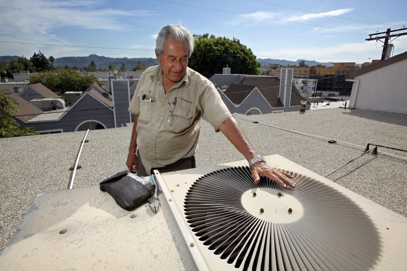 Even though the air coming out is pretty warm, Al Manzano, founder of A&M Refrigeration Co., cools his hand on the vent fan outlet on an air conditioning unit on the roof of an apartment building in the North Hollywood district of Los Angeles Tuesday, Sept. 28, 2010. Tuesday temperatures, while not as high as the previous day, continued near the triple-digit mark, with elevated humidity for overall muggy weather, in many parts of Southern California. (AP Photo/Reed Saxon)