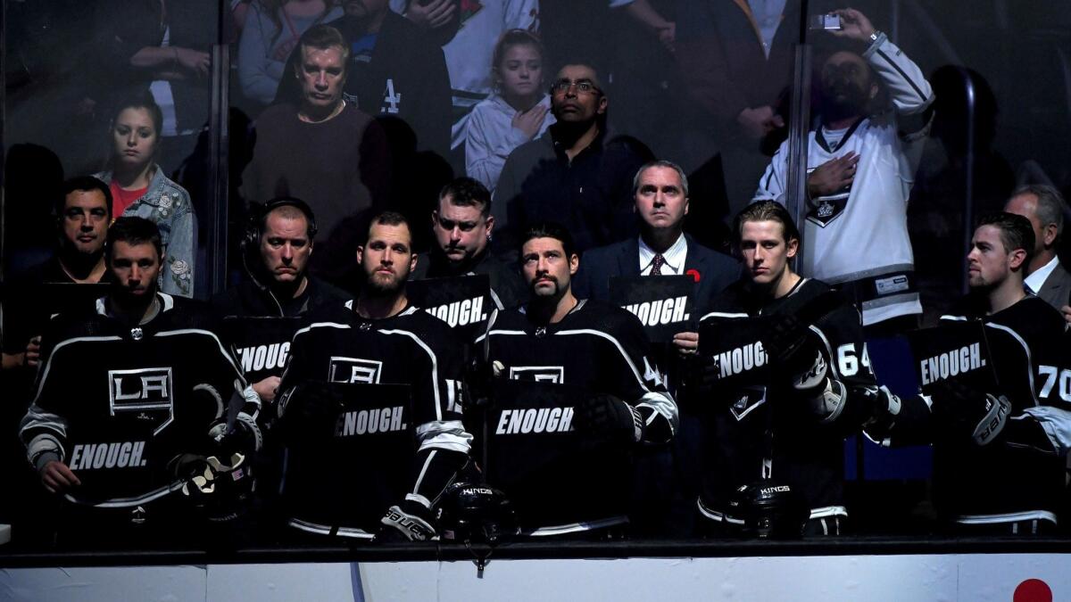 Kings players hold up signs with the word "Enough" in reaction to the mass shooting in Thousand Oaks.