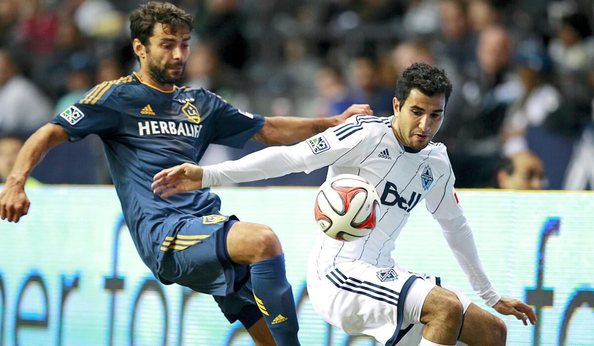 Galaxy midfielder Baggio Husidic vies for the ball with Vancouver's Steven Beitashour during a game earlier this season.