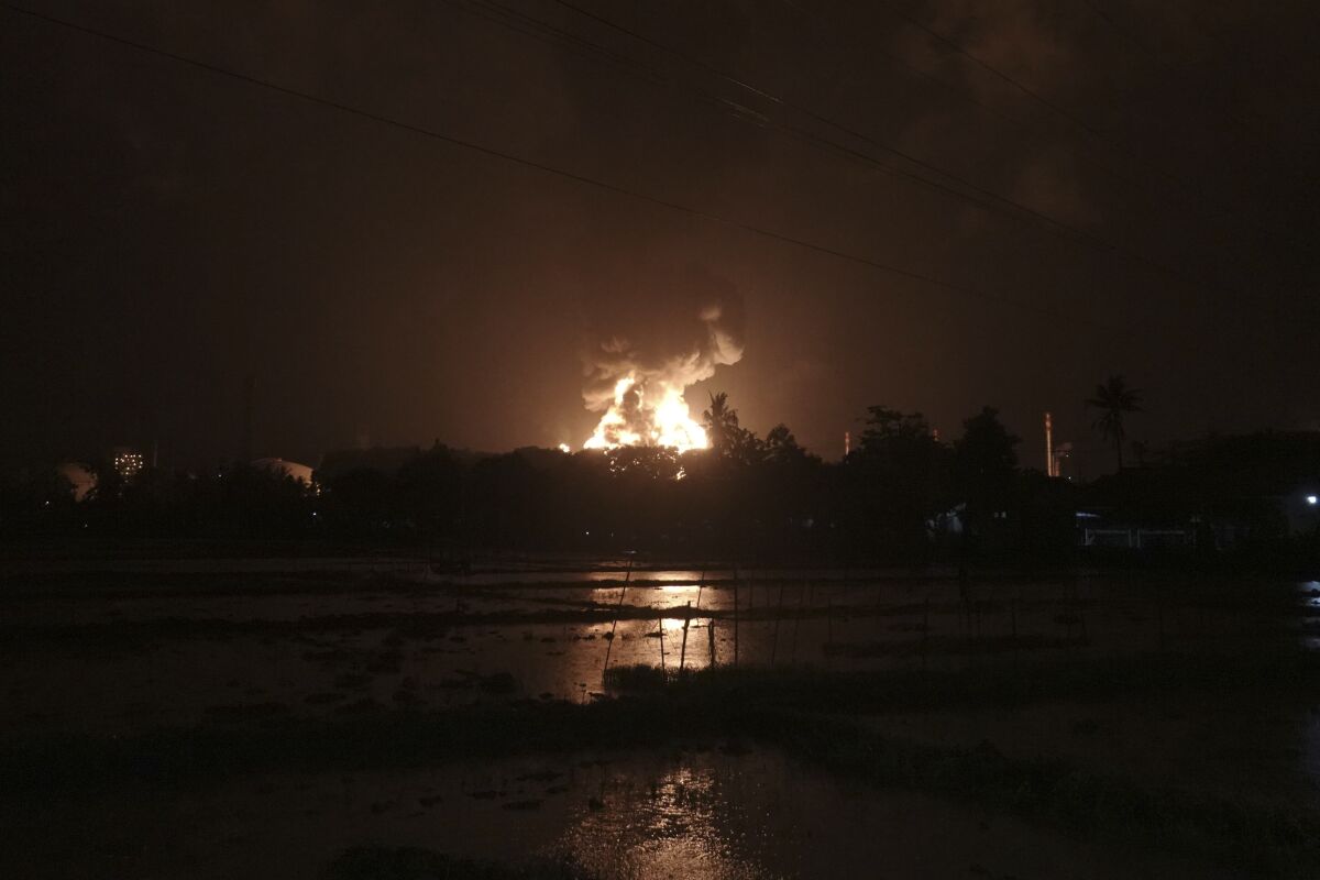 The sky glows from the fire that razes through an oil refinery owned by the national oil company Pertamina, in Cilacap, Central Java, Indonesia, Saturday, Nov. 13, 2021. The fire at a gasoline storage at the largest oil refinery on Indonesia's Java island prompted the evacuation of dozens of residents living nearby. (AP Photo/Agus Fitrah)