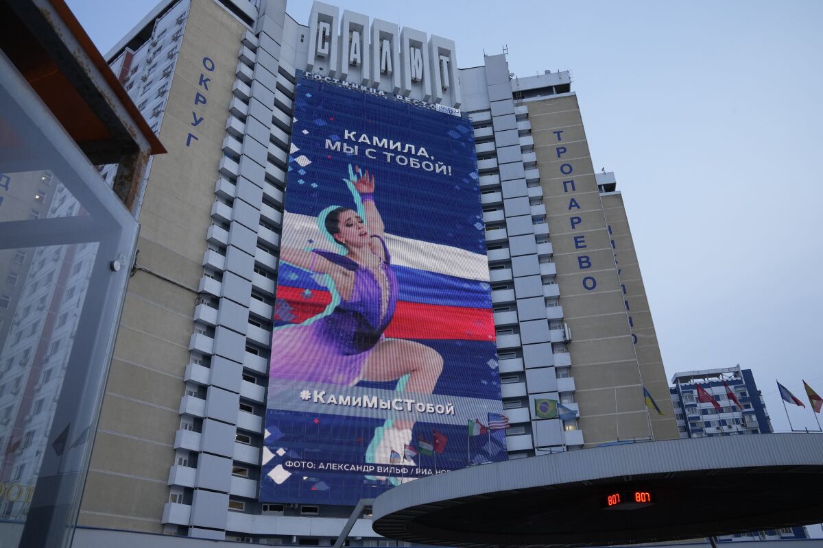 A huge electronic billboard shows a photo of Kamila Valieva with words "Kamila, we are with you" on the building of the Salut hotel in Moscow, Russia, Monday, Feb. 14, 2022. Russian teenager Kamila Valieva has been cleared to compete in the women's figure skating competition at the Winter Olympics despite failing a pre-Games drug test. (AP Photo/Alexander Zemlianichenko)