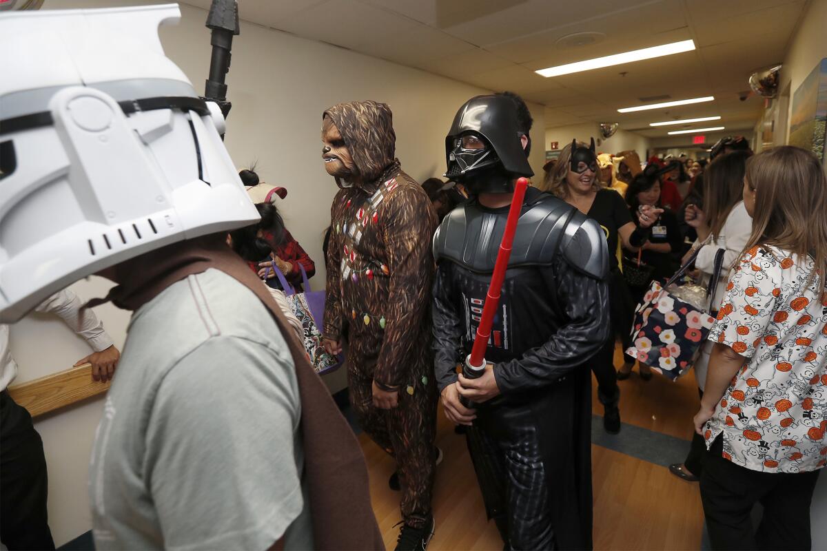 Costumed doctors and staff members turn out for a Halloween trick-or-treat parade in a hallway at Fountain Valley Regional Hospital & Medical Center on Thursday morning.