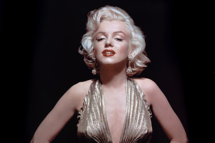 Marilyn Monroe posing in a gold lame gown