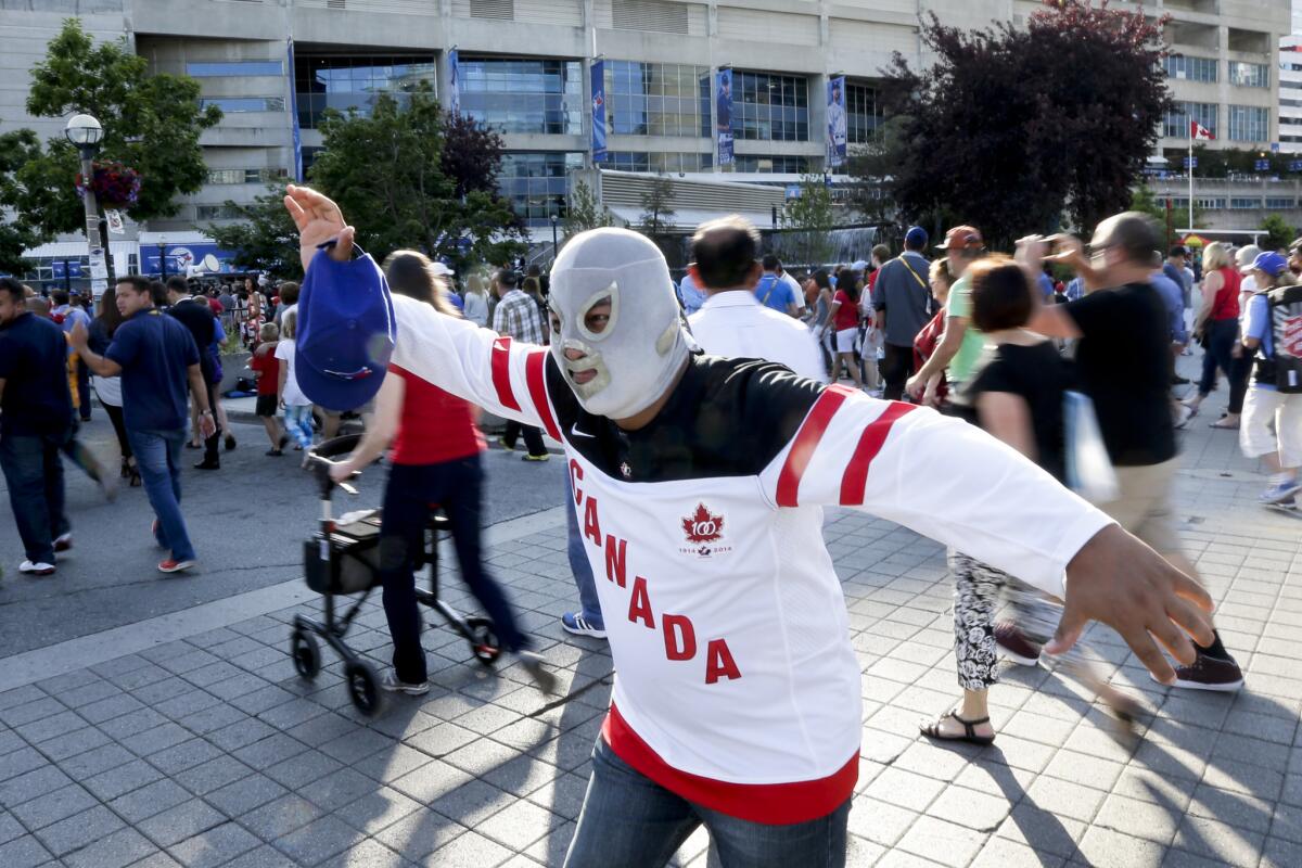 A fan wears a Mexican wrestling mask and a Canadian hockey jersey as he poses for a photo before the opening ceremony for the Pan Am Games in Toronto, Friday, July 10, 2015. (AP Photo/Gregory Bull)