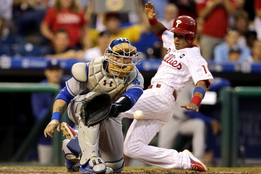 The Philadelphia Phillies' Cesar Hernandez scores past Dodgers catcher Yasmani Grandal on an RBI double during the third inning on Tuesday.