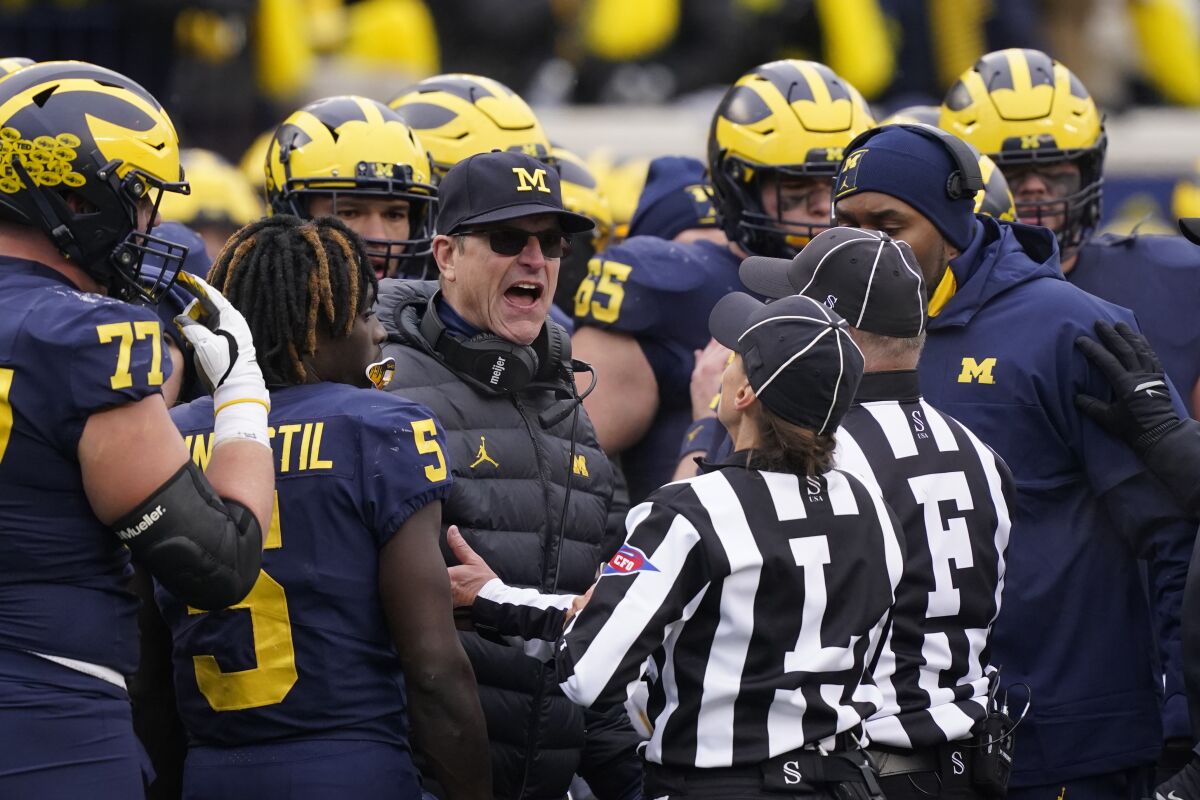 Referees talk to Michigan head coach Jim Harbaugh during the second half of an NCAA college football game against Ohio State, Saturday, Nov. 27, 2021, in Ann Arbor, Mich. (AP Photo/Carlos Osorio)