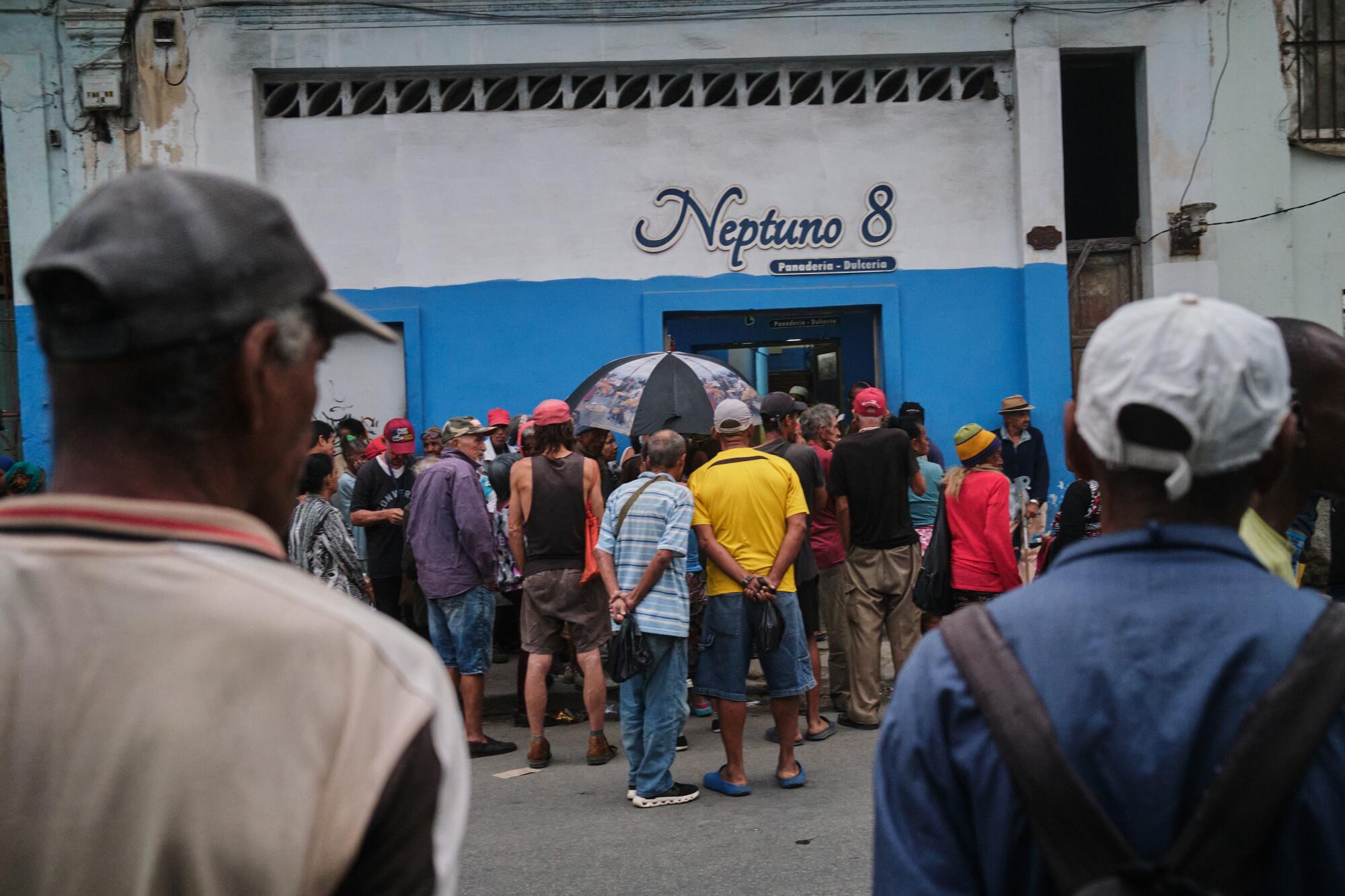 People wait in the rain to collect bread.