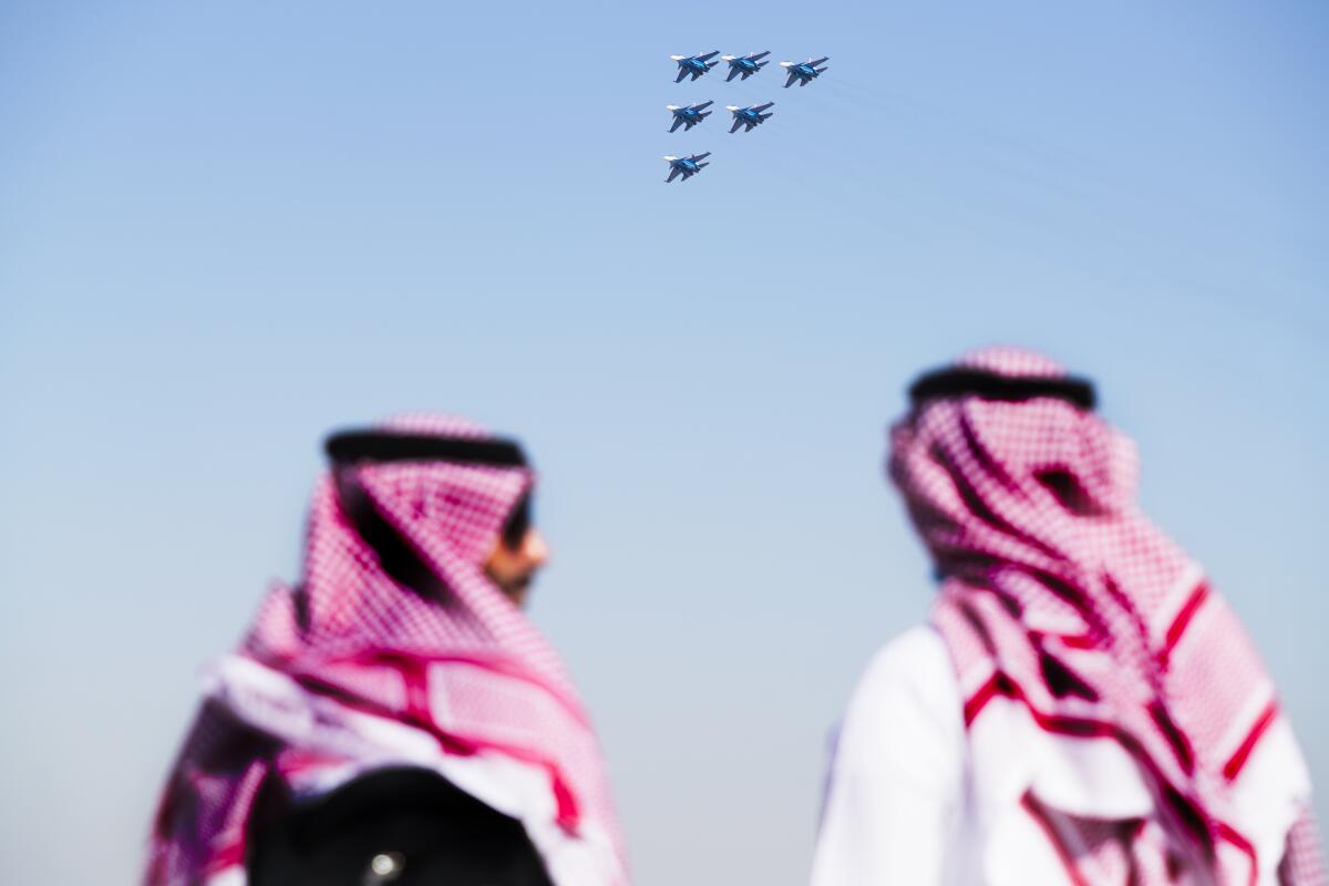 Two Arab men watch as the Russian Knights perform a stunt at the Dubai Air Show