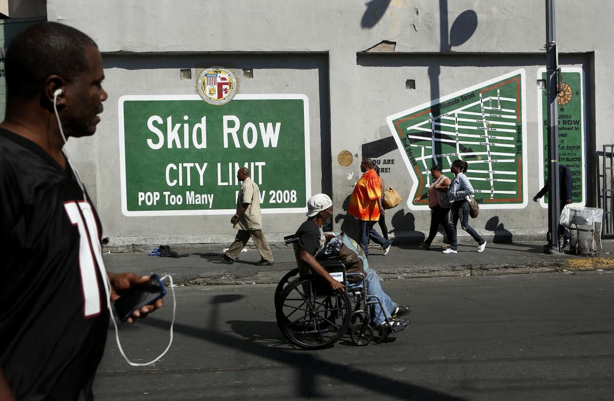 A wall mural in skid row in downtown Los Angeles as people pass by.