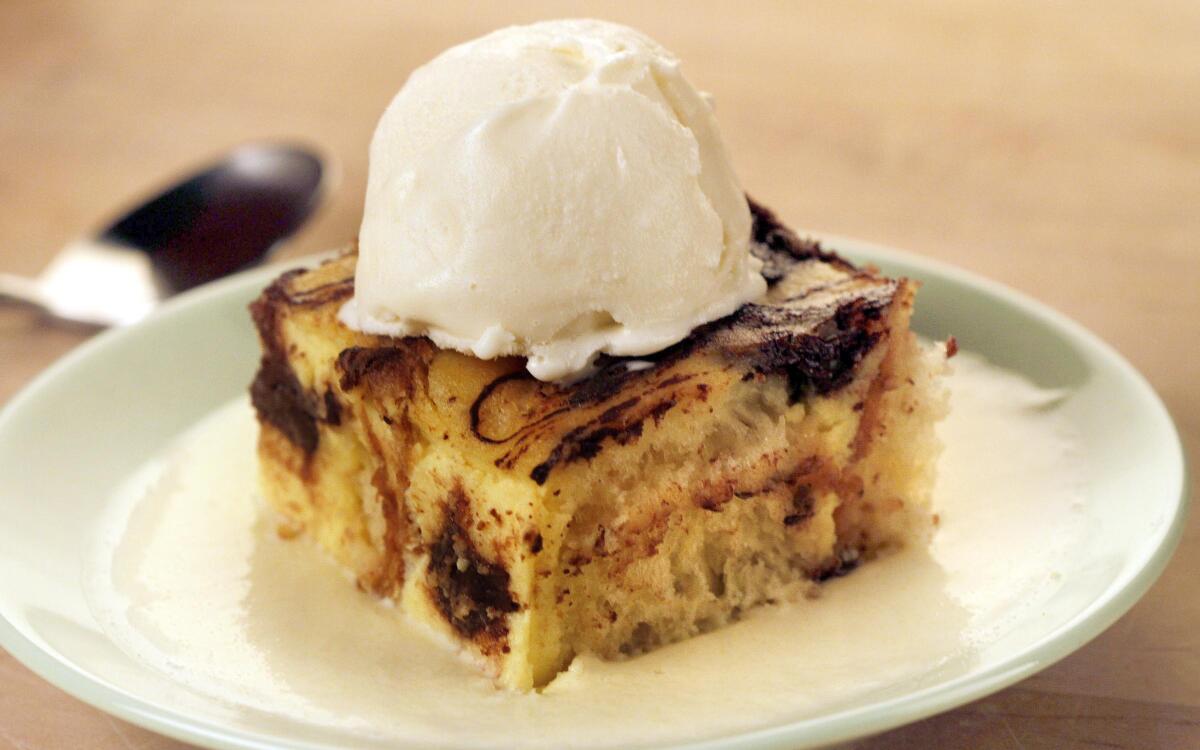 A serving of Chocolate Brioche Bread Pudding garnished with a scoop of vanilla bean ice cream on a small white plate.