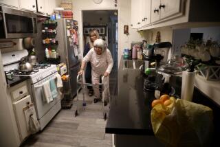 NORTHRIDGE, CA - SEPTEMBER 11, 2023 - Mariella Rojas helps her mother Rosa Angelica Saldana, 81, walk through the kitchen to her favorite chair in the dining room of their apartment in Northridge on September 11, 2023. Saldana, who suffers from dementia, lives with her daughter and her family in a three bedroom apartment. Saldana has lived with her family for the past seven years. As the population ages, and costs of care becoming crippling, many families, like the Rojas family, take care of an elder family member themselves out of cultural tradition and financial necessity. (Genaro Molina / Los Angeles Times)