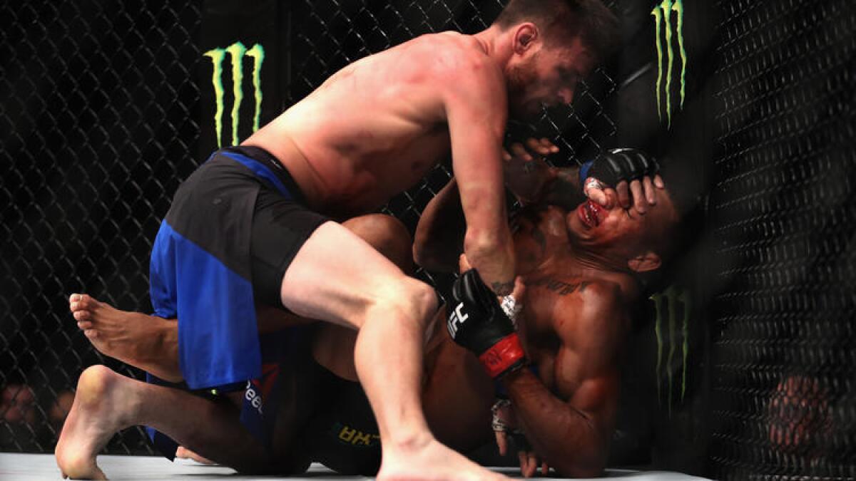 Tim Means (blue trunks) grapples with Alex Oliveira after taking him down during their welterweight bout at UFC 207.