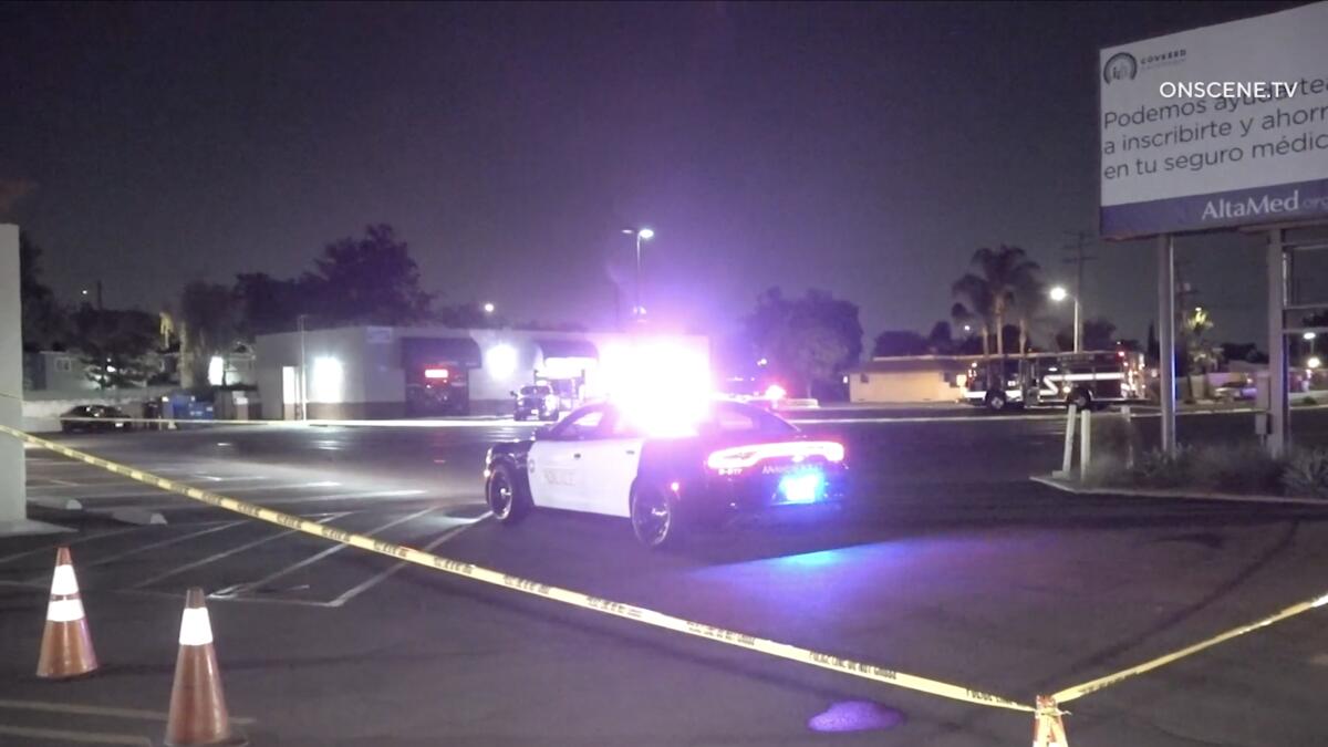 A squad car is surrounded by police tape.