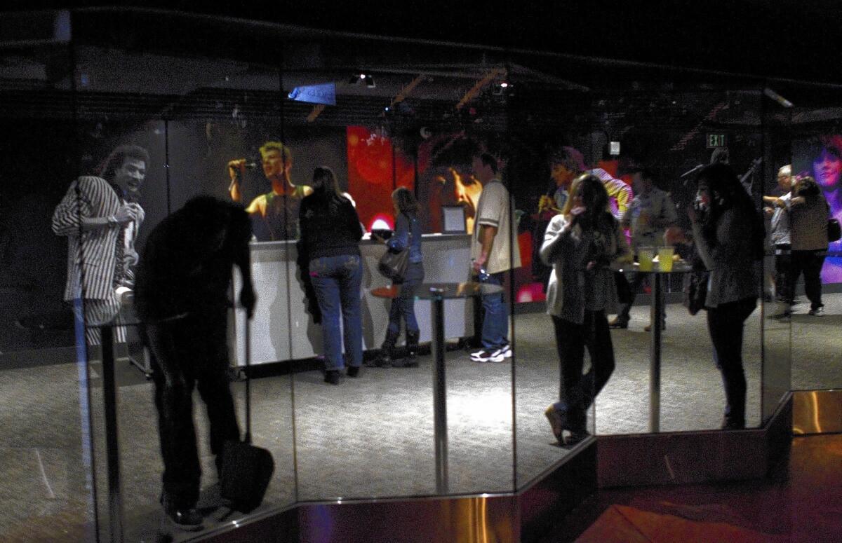 Patrons watch the opening act through glass doors as others stand in line at a floor bar during the Eagles' concert at the newly renovated Forum in Inglewood.