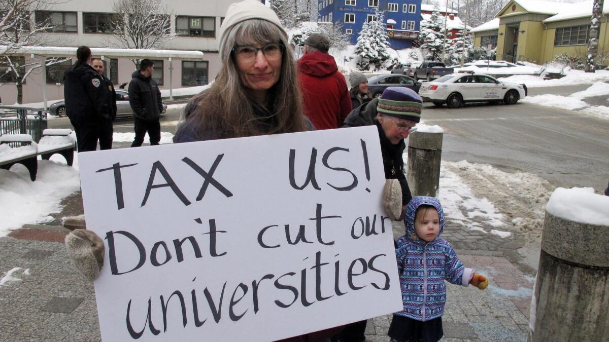 Luann McVey holds a sign before a rally in support of the Alaska university system on Feb. 13 in Juneau.