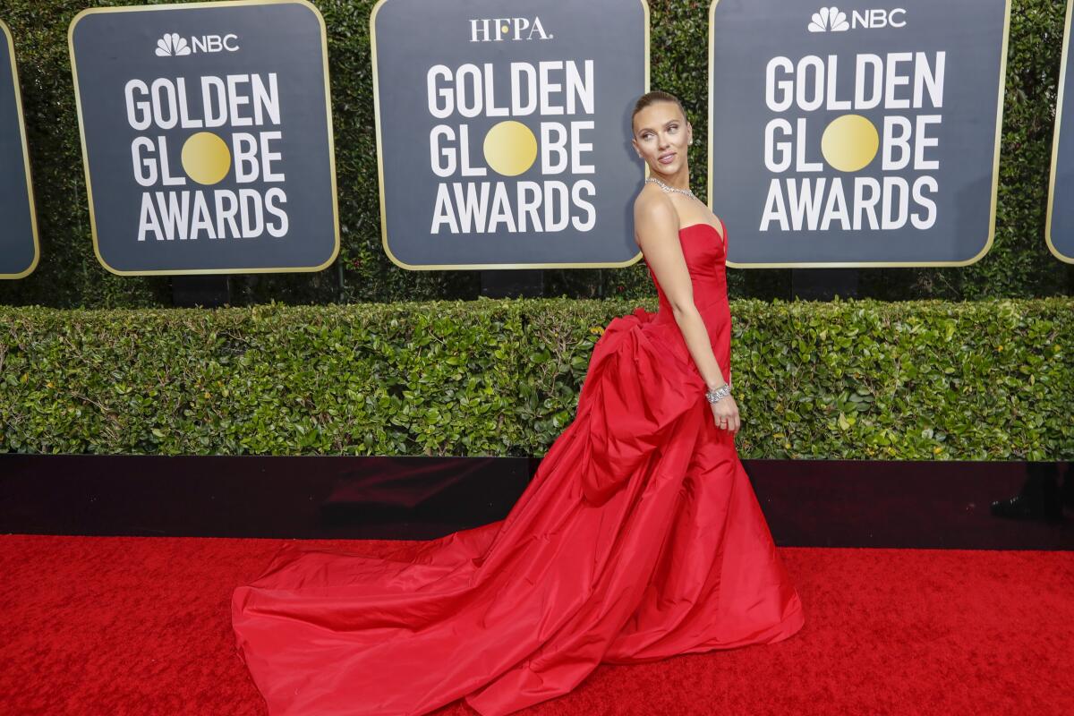 Actress Scarlett Johansson in a long red gown on the red carpet in front of signs that say Golden Globe Awards