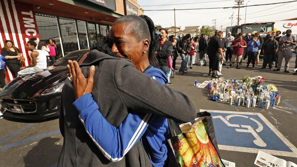 LaShanna Ayers, right, whose grandson is a godson to Nipsey Hussle, is comforted in the parking lot at 3420 W. Slauson where Hussle was killed and two others were wounded.