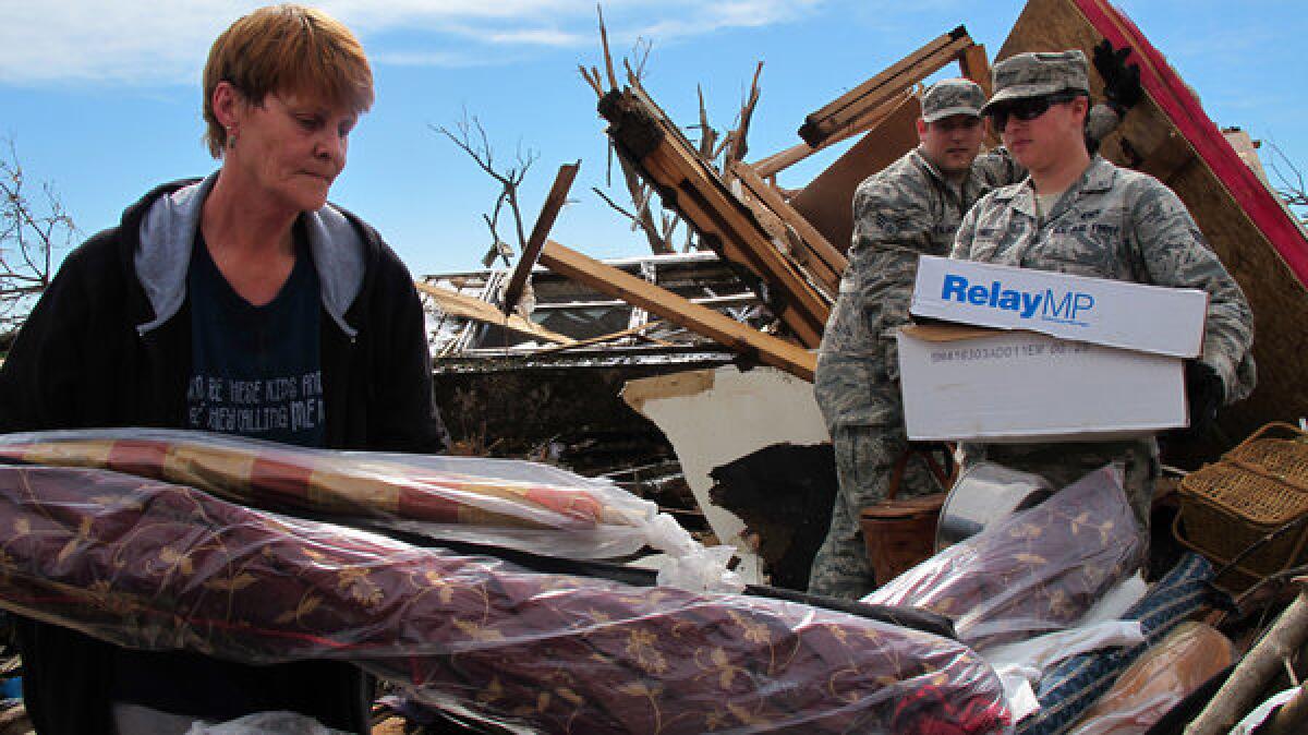 Josephine Owings, 62, who survived a direct hit by a tornado on her rented home in Moore, Okla., Monday afternoon, gets help recovering belongings Tuesday. Owings returned to salvage items from her home-based seamstress business.