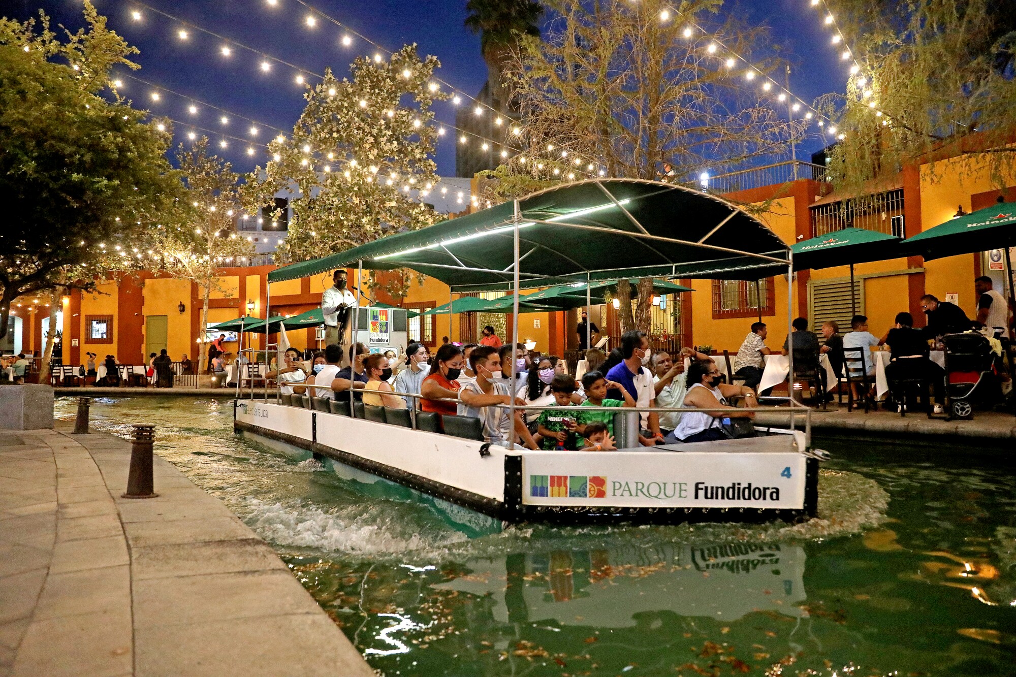 Diners eat al fresco while a tour boat goes by.