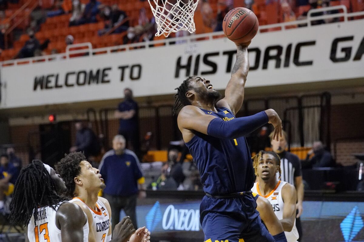 West Virginia forward Derek Culver, center, shoots in front of Oklahoma State guards Isaac Likekele (13) Cade Cunningham (2) and Rondel Walker, right, in the first half of an NCAA college basketball game Monday, Jan. 4, 2021, in Stillwater, Okla. (AP Photo/Sue Ogrocki)