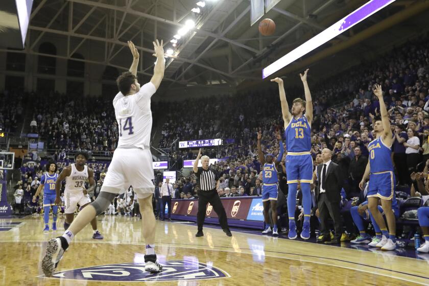 UCLA's Jake Kyman (13) puts up a 3-point shot with seconds left as Washington's Sam Timmins (14) moves in to defend during an NCAA college basketball game Thursday, Jan. 2, 2020, in Seattle. Kyman made the shot and UCLA won 66-64. (AP Photo/Elaine Thompson)