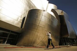 LOS ANGELES, CA - MARCH 22: Alex Espadero with Sunrise Window Cleaning uses a special extension wand to clean the metal of Walt Disney Concert Hall on Monday March 22, 2021. The 179,150 square feet of metal is cleaned once a year but takes over one month to complete the cleaning. 45 percent of the building is cleaned by workmen on a scaffold but the remaining 55 percent is by hand using the special wand using ionized water. Regular water would leave stains. The first 4 panels up from the ground are cleaned 3¬n4 times a week sometimes using joy soap to get the finger prints off. The cleaning is usually in preparation for the Los Angeles Philharmonic summer opening but plans for 2021 remain on hold due to COVID-19. Disney Hall on Monday, March 22, 2021 in Los Angeles, CA. (Al Seib / Los Angeles Times).