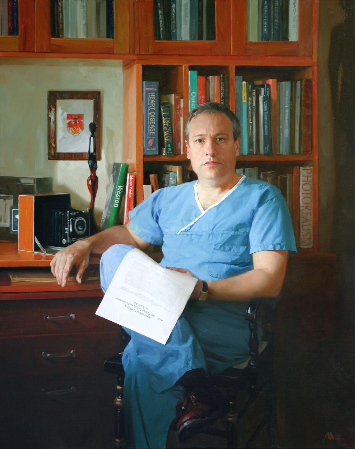 Dr. C. Michael Gibson, dressed in scrubs, sits in a book-lined office. 