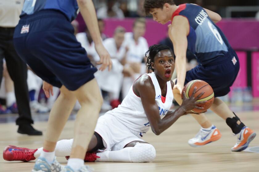 FILE - France's Emilie Gomis looks to pass as she is flanked by Britain's Stef Collins, right, and Natalie Stafford during a women's basketball game at the 2012 Summer Olympics, Friday, Aug. 3, 2012, in London. The former France basketball player serving as an ambassador for the Paris 2024 Olympics has been forced to step down because of a controversy linked to a social media post related to the situation in Gaza. (AP Photo/Charles Krupa, File)
