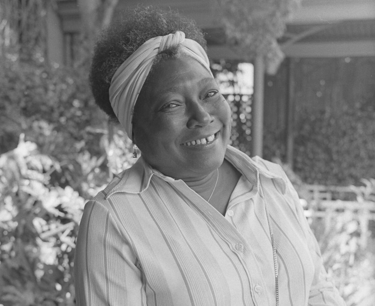 A woman in a striped blouse smiles for a photo.