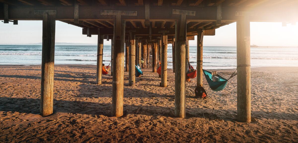 Hammocks hang under a pier that leads into the Pacific Ocean