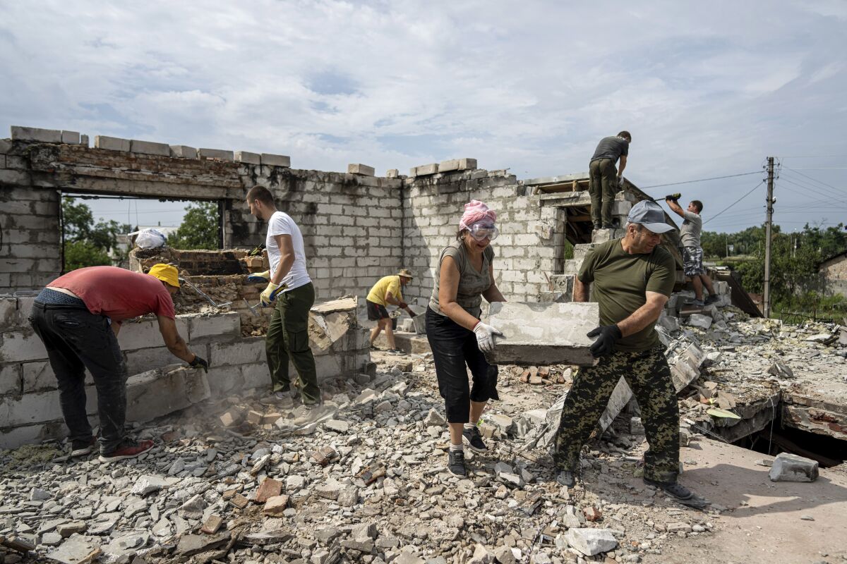 Volunteers in the Ukrainian village of of Novoselivka clear rubble from a demolished home.