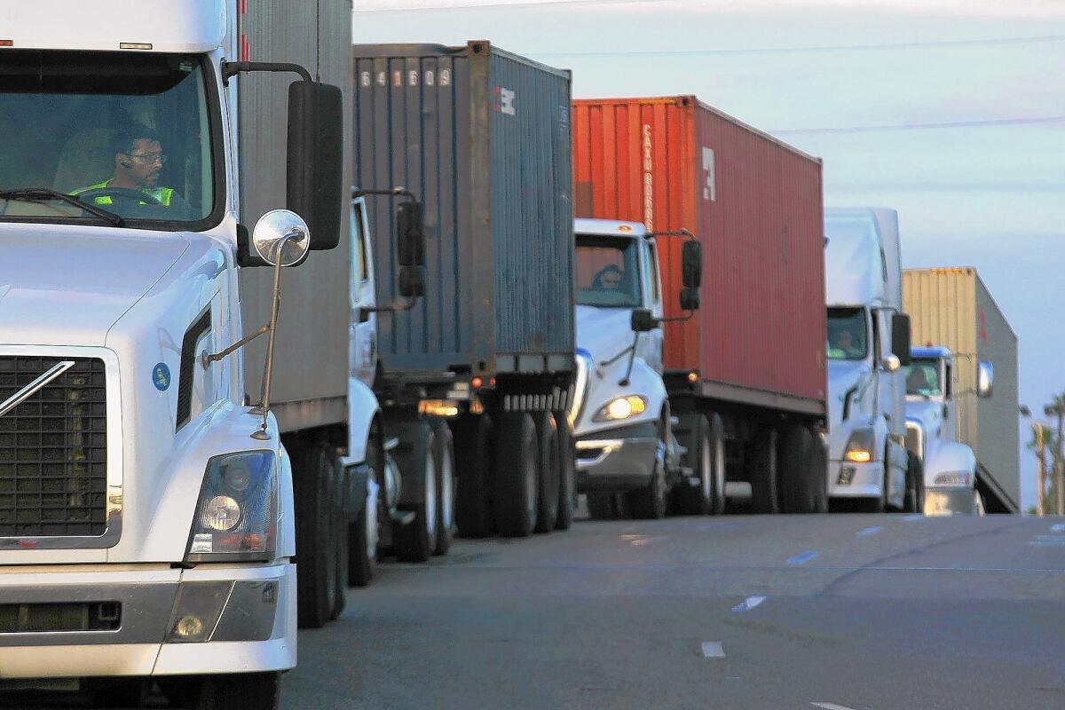 Port truck drivers have filed lawsuits and have flooded the state with hundreds of claims alleging that port trucking firms improperly classified them as independent contractors rather than employees. Above, trucks wait in line to take cargo to a pier in the Port of Long Beach in April.