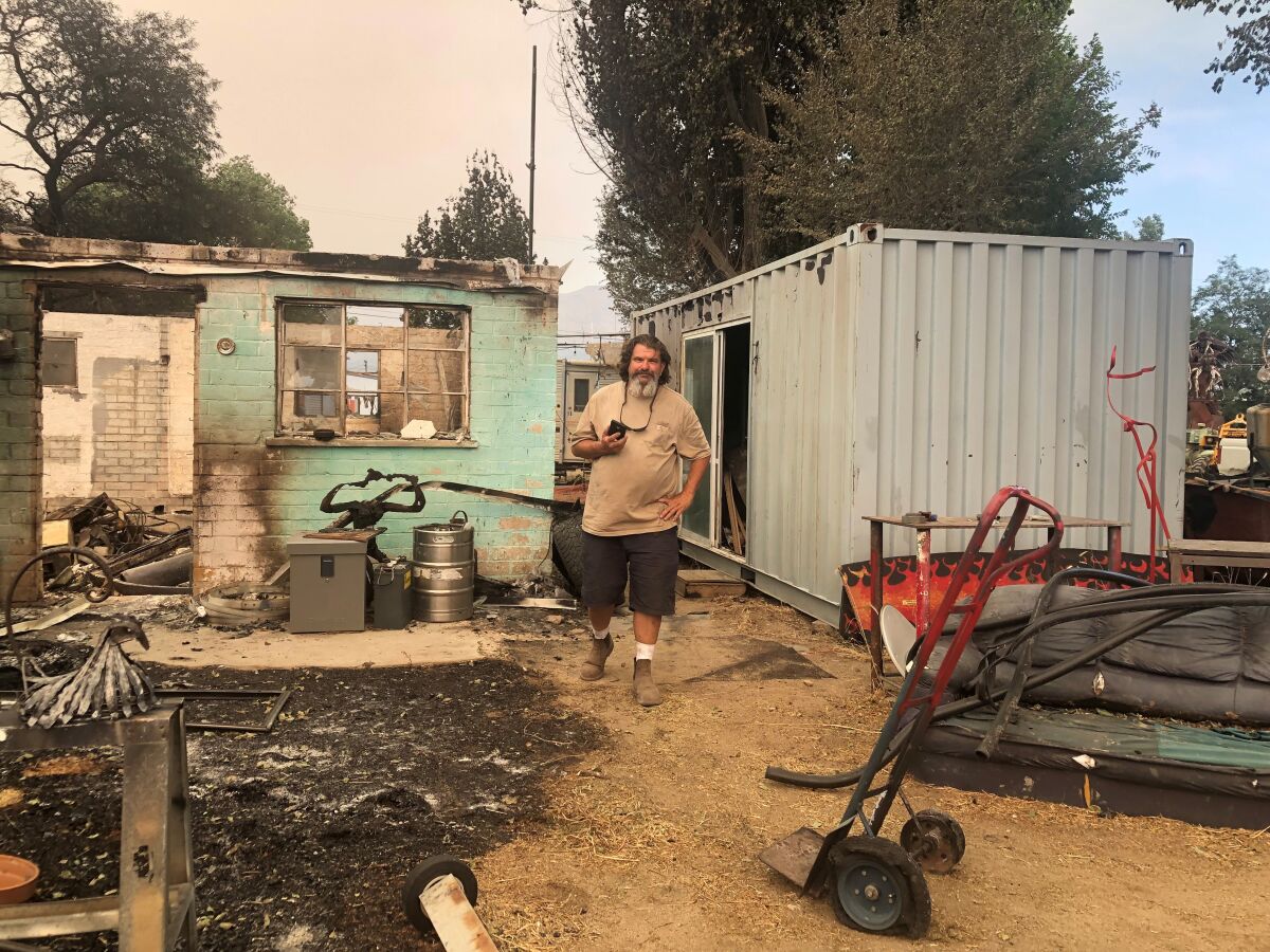 A man stands alongside a charred home.