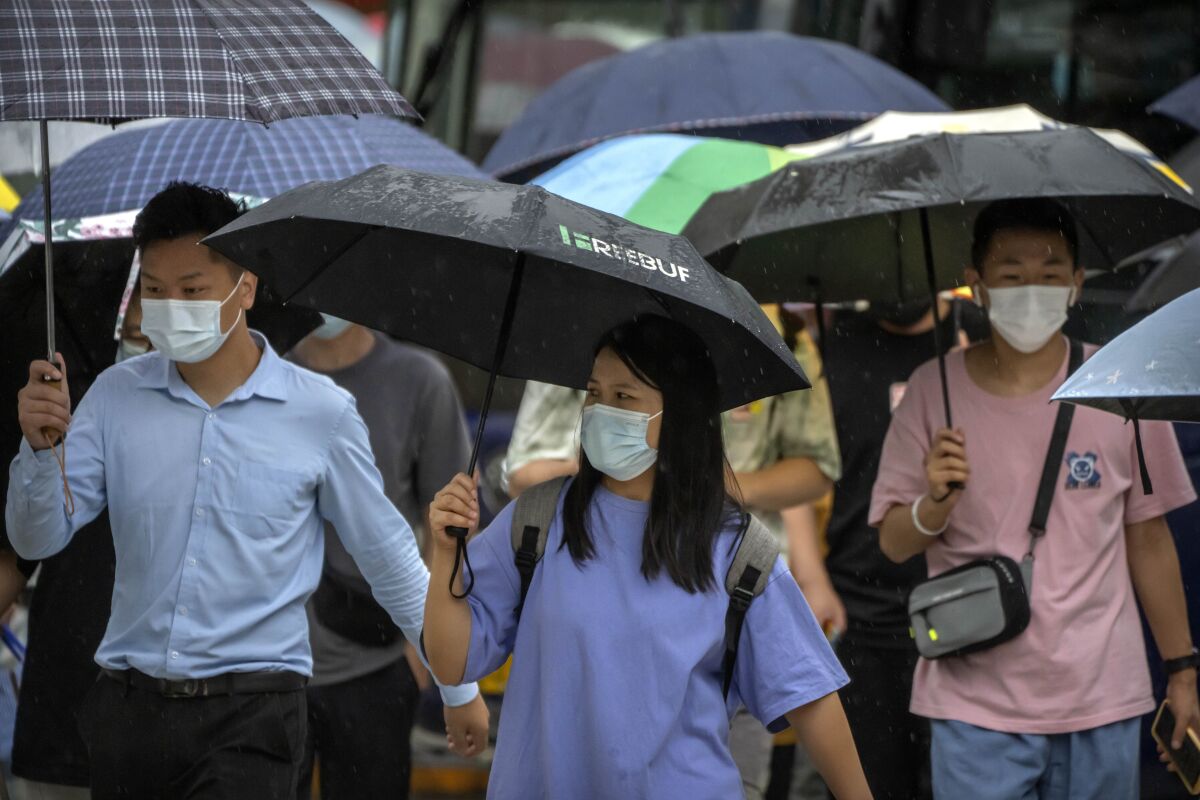 Personas con cubrebocas caminan por una calle del distrito comercial de Beijing, el 9 de agosto de 2022. 