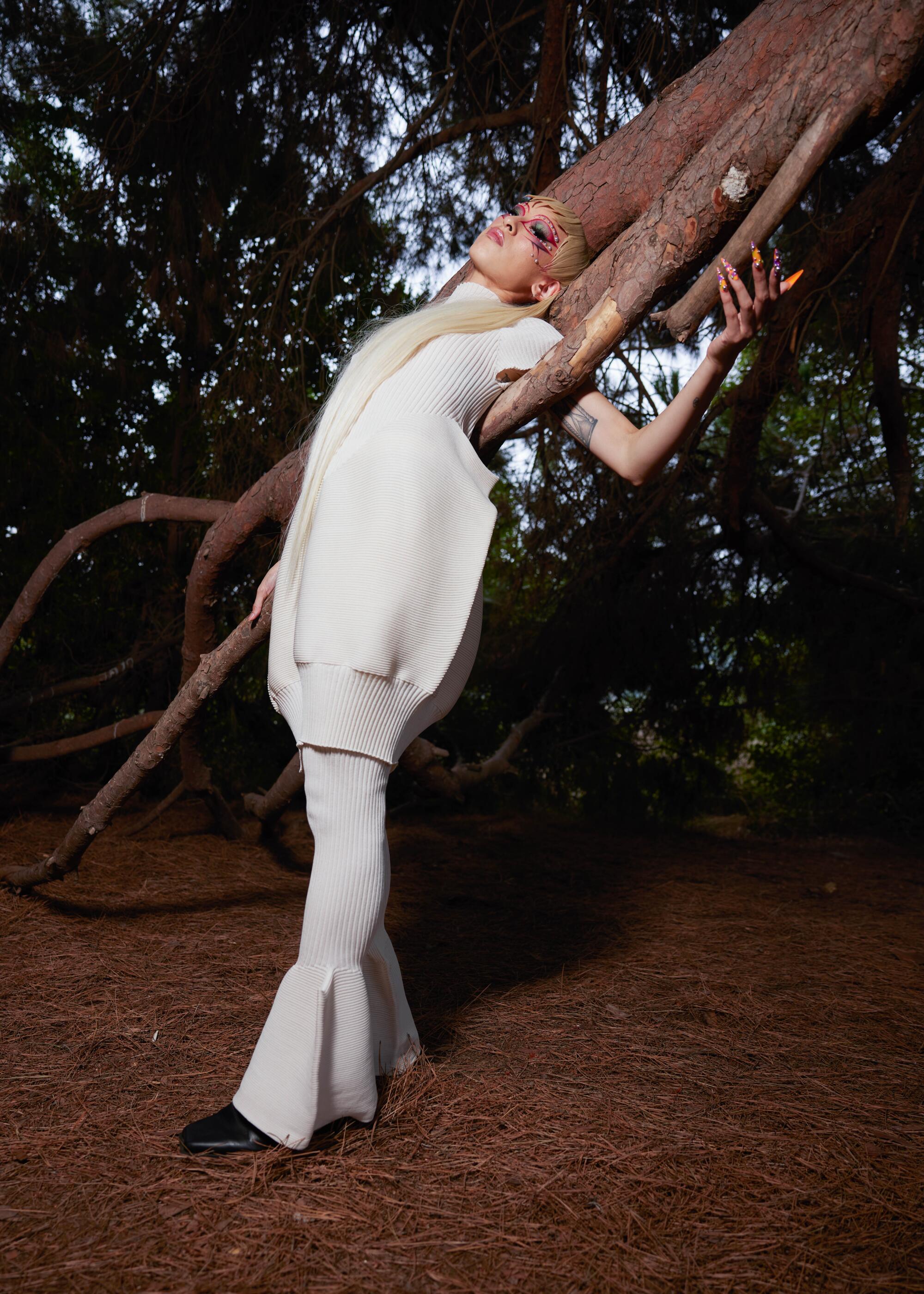 A model in a white Issey Miyake outfit seems almost to become part of the tree branch seemingly growing from her head
