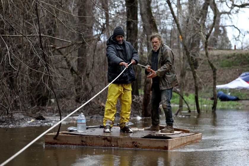 SACRAMENTO, CA - JANUARY 04: Dyrone (cq) Woods, 50, left, who is homeless, and Jeff "Big Jeff," 58, originally of Tucson, Arizona, who is homeless, use a raft to get back and forth from the roadway to a homeless encampment on Bannon Island, along the Sacramento River on Wednesday, Jan. 4, 2023 in Sacramento, CA. Woods has lived over five years at the homeless encampment of the island. Jeff has lived at the homeless encampment for 12 years. The storms last week caused flooding on the island, roughly 50 people who live in the encampment have being warned to move to higher ground. Massive 'atmospheric river' to bring heavy rains, winds, flooding across California. Residents, business owners and emergency workers nervously await the epic 'Bomb cyclone' storm expected to slam the Bay Area Wednesday and Thursday. Urgent high wind warning starting at 4 a.m. Wednesday, with gusts up to 50 mph in low-lying areas and up to 70 mph at the coast and among the region's highest peaks. (Gary Coronado / Los Angeles Times)