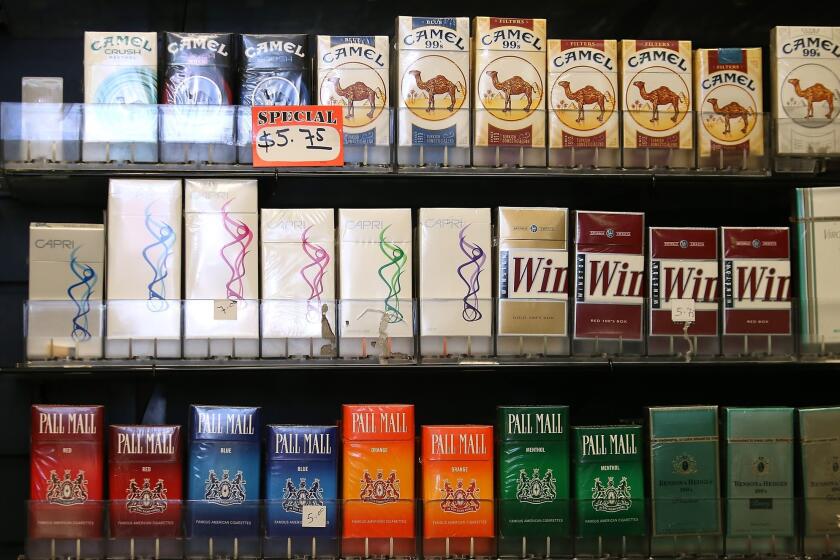 Cigarette brands manufactured by Reynolds American are displayed at a tobacco shop in San Francisco. The tobacco giant agreed to merge with Lorillard Inc. in a $27.4-billion deal.