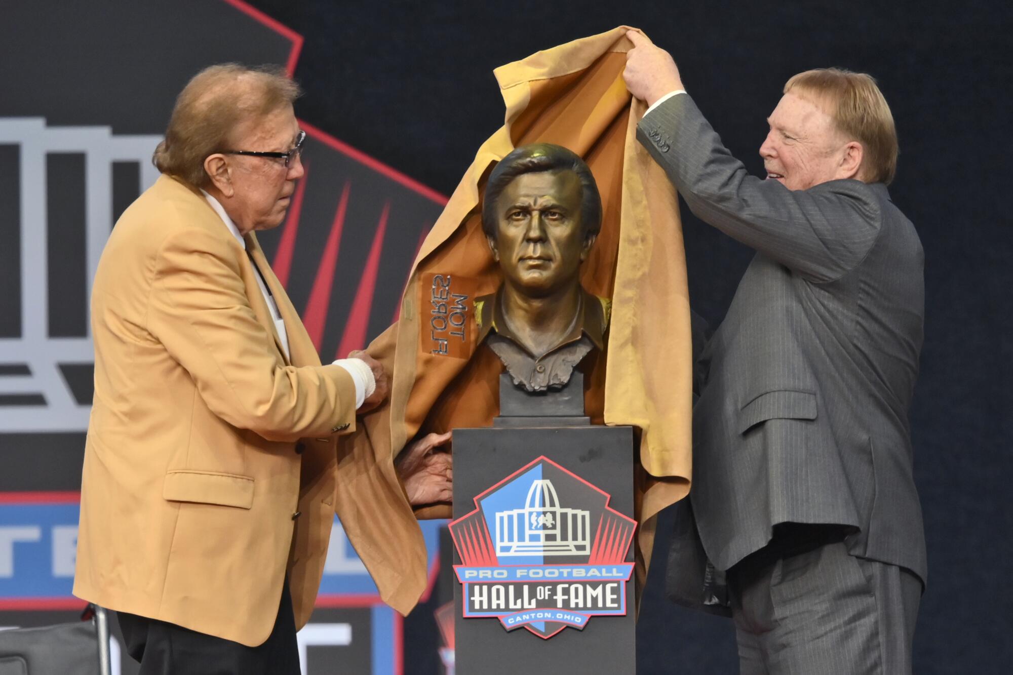 Tom Flores and Raiders owner Mark Davis unveil the bust of Flores at the induction ceremony at the Pro Football Hall of Fame.